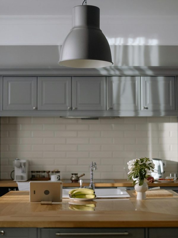 A sleek kitchen with gray cabinets, wooden countertops, and modern lighting.
